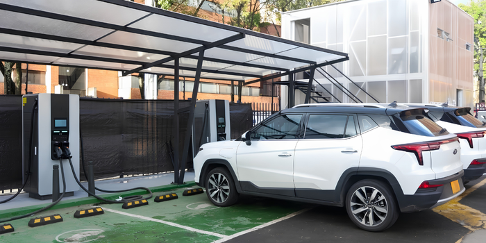 Vehículos eléctricos estacionados junto a cargadores en una zona de recarga