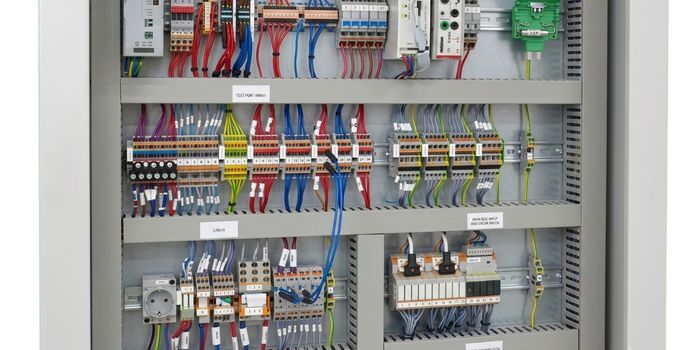Interior maquetado de un tablero de control eléctrico industrial automatizado con filas estructuradas de borneras Push In Cabur cableadas con hilos rojos y azules para distribución de carga y bloques de interconexión de seguridad